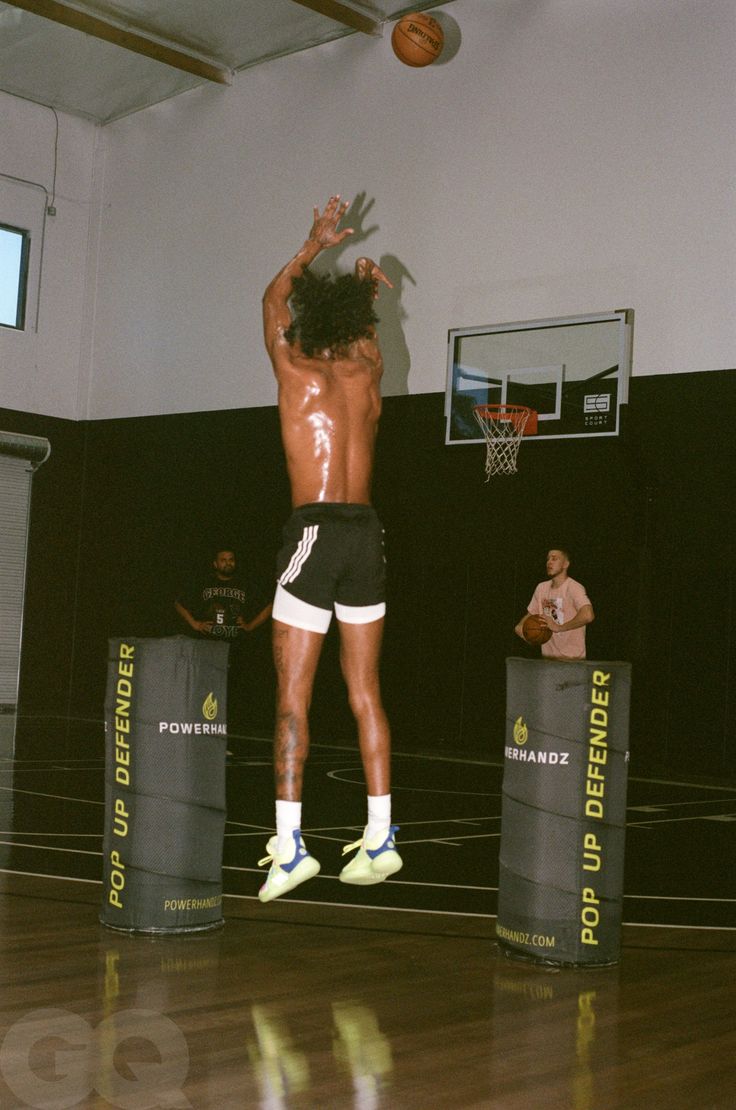 a man jumping up in the air to dunk a basketball on a gym court