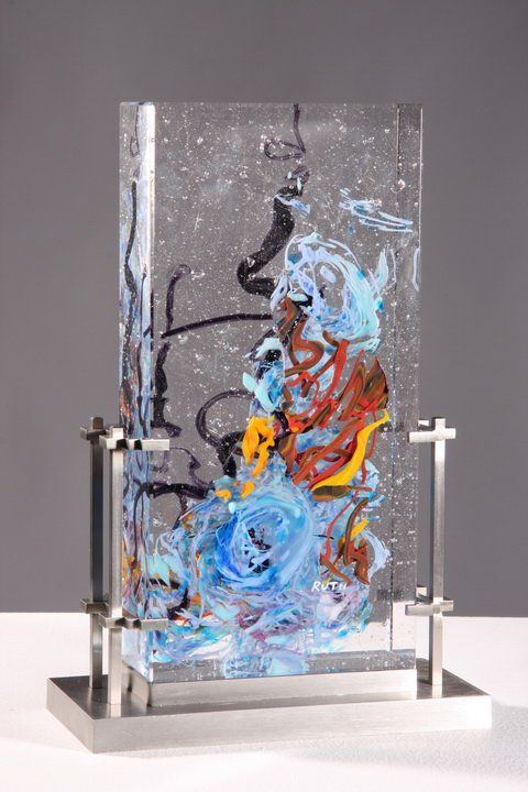 a glass block with some paint and water on it's sides, in front of a gray background