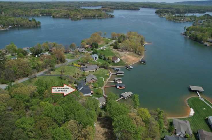 an aerial view of a lake surrounded by trees and houses with a red arrow pointing to the right