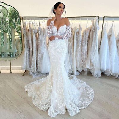 a woman standing in front of a rack of wedding gowns and looking at the camera