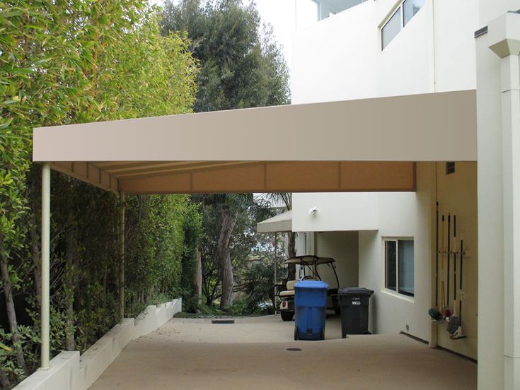 an outdoor covered patio with trees and trash cans