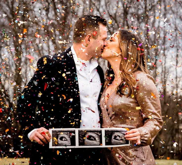 a man and woman are kissing in front of confetti falling from the sky