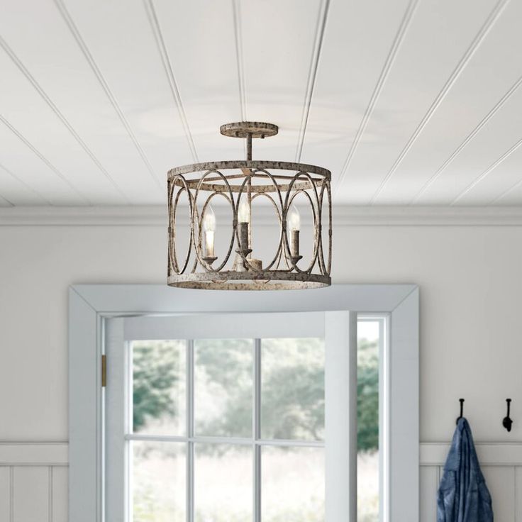 a light fixture hanging from the ceiling in a room with white walls and wood flooring