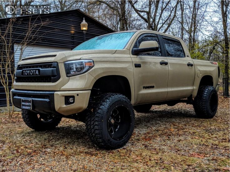 a tan toyota tundra is parked in front of a building with trees and leaves on the ground