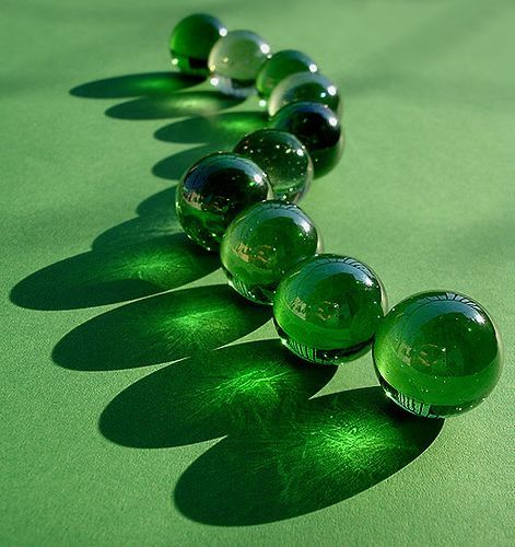 a row of green glass balls sitting on top of a green table next to each other