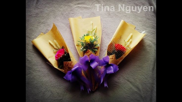 three flowers are wrapped in brown paper with purple ribbons on the bottom, and one flower is yellow