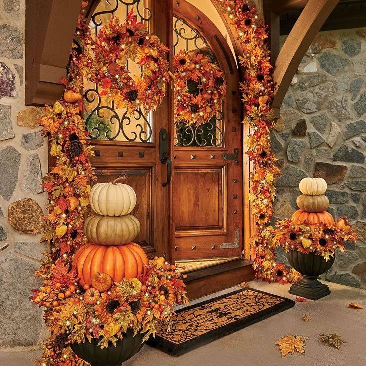 an autumn scene with pumpkins and gourds in front of a house door