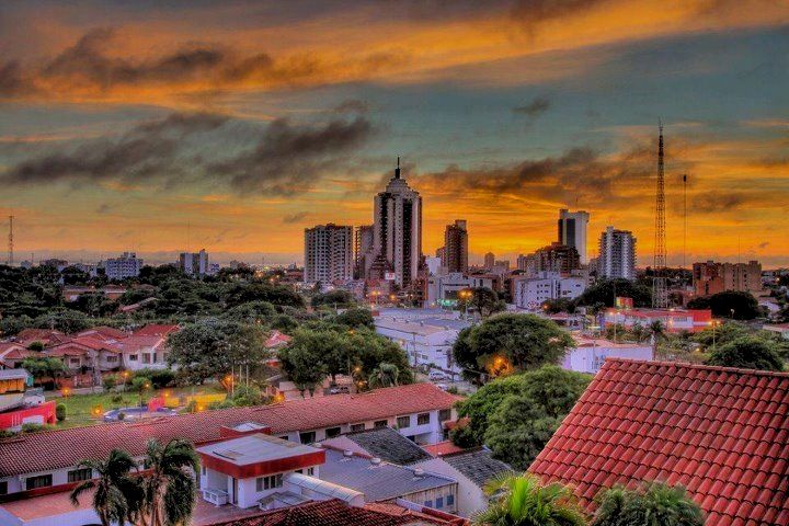 the city skyline is shown at sunset in this photo, with red roofs and tall buildings