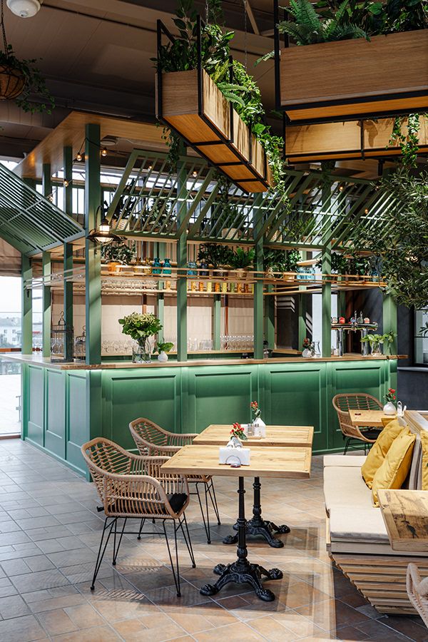 the interior of a restaurant with tables, chairs and plants hanging from the ceiling above