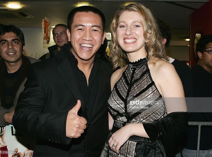 a man and woman standing next to each other at an event with people in the background