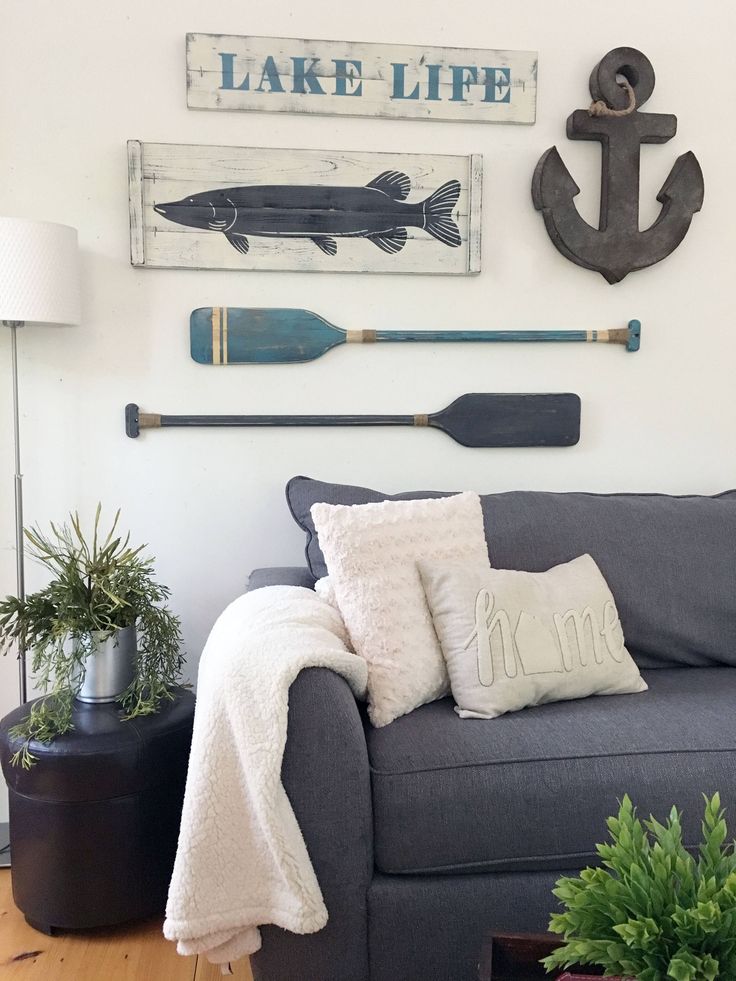 a living room with a gray couch and various items on the wall above it that says lake life