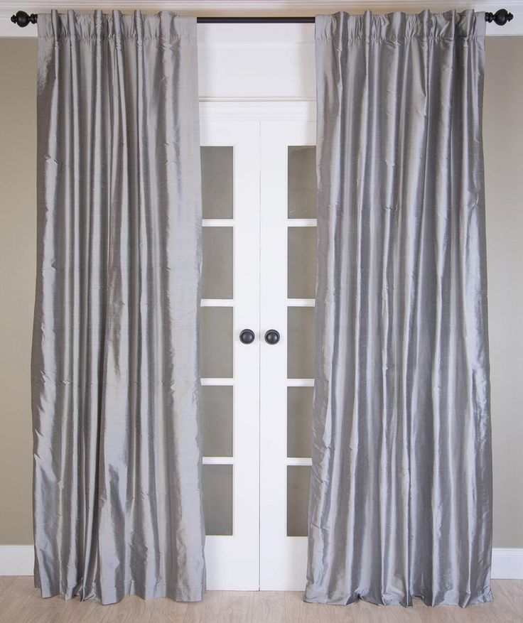 a pair of silver curtains hanging on the side of a white door in front of an open bookcase