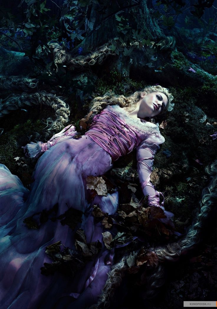 a woman laying on the ground surrounded by leaves and vines in a purple dress with her eyes closed