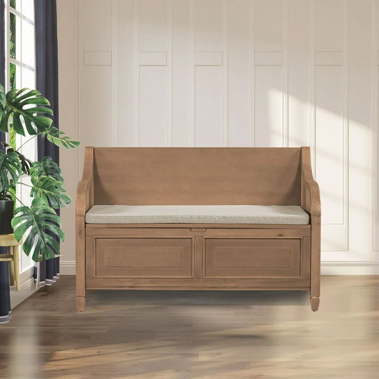 a wooden bench sitting next to a potted plant on top of a hard wood floor