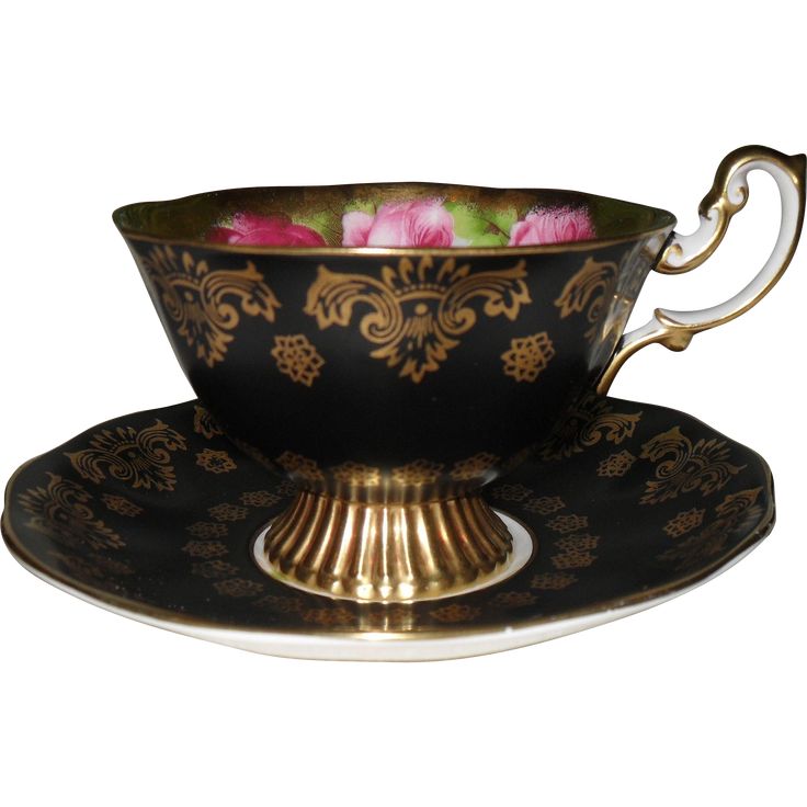 a black and gold tea cup with pink flowers in it on a saucer set