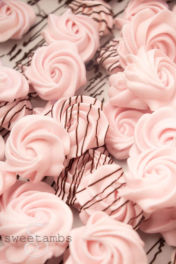 there are many pink frosted chocolates on the table with swirly icing