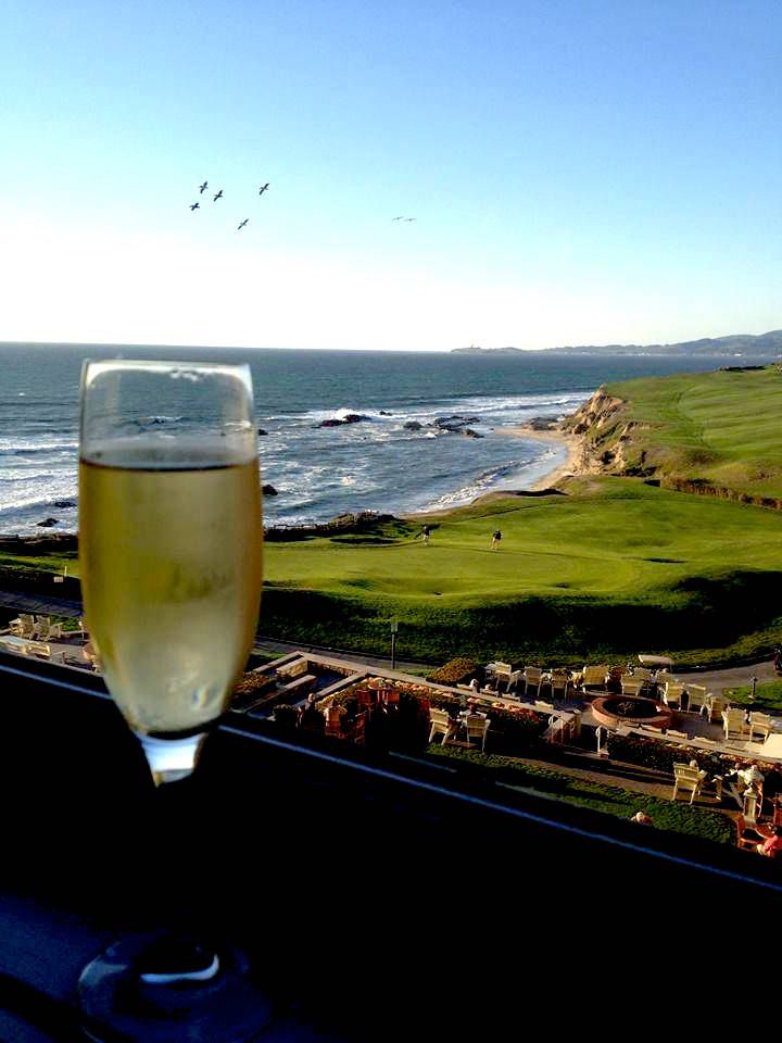 a glass of wine sitting on top of a window sill next to the ocean