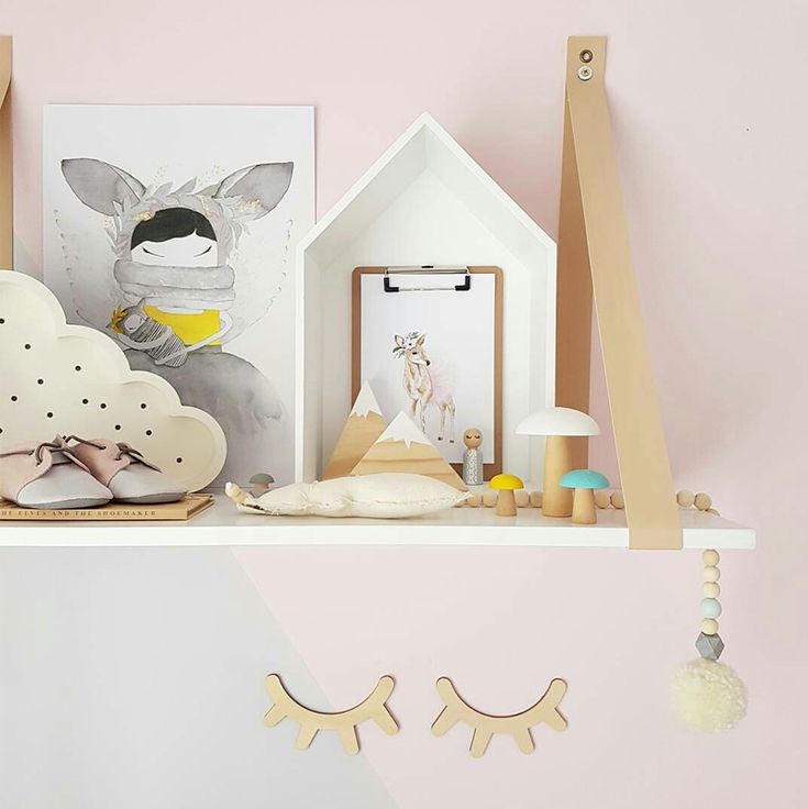 a shelf with various items on it in a room that has pink walls and white furniture