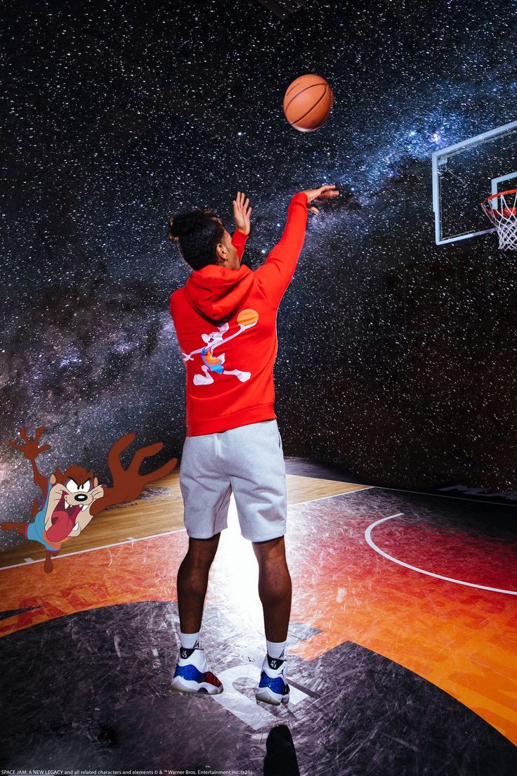 a man in red shirt and white shorts shooting a basketball at the hoop with stars above him