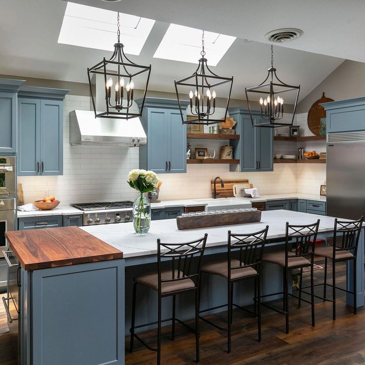 a kitchen with blue cabinets and an island in the middle, surrounded by wooden flooring