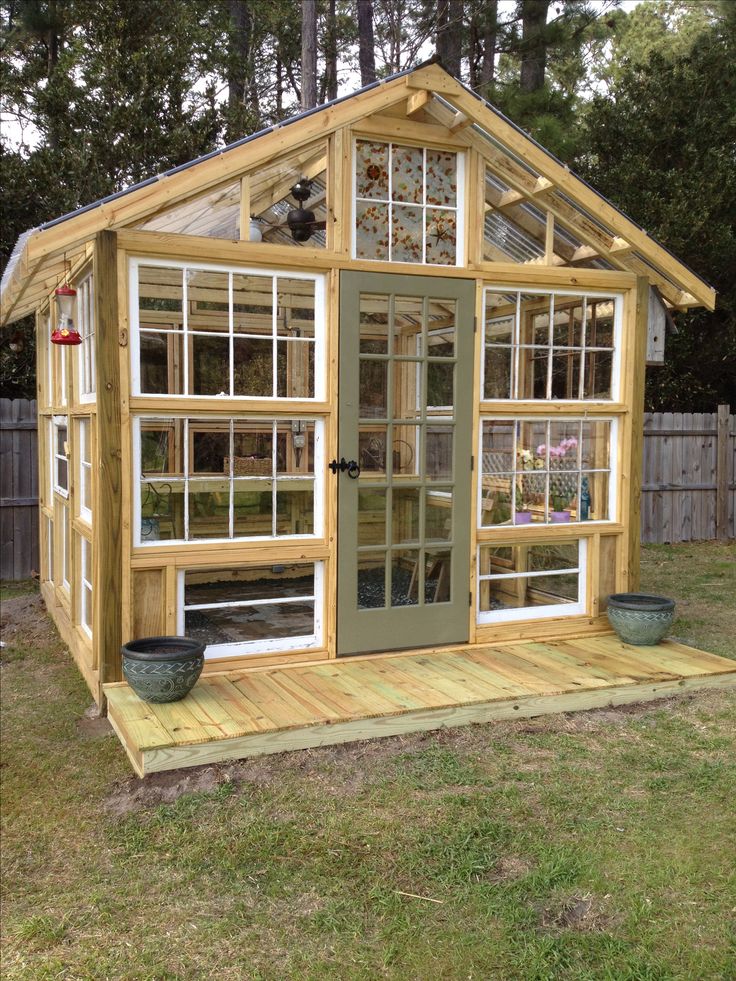 a small wooden greenhouse with windows on the roof