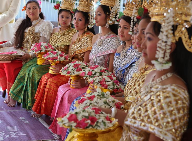 a group of women dressed in traditional thai garb sitting at a table with flowers on it