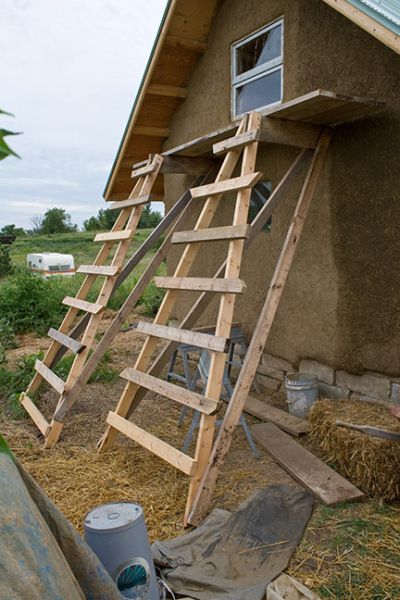 a ladder leaning up against the side of a house next to straw bales and hay