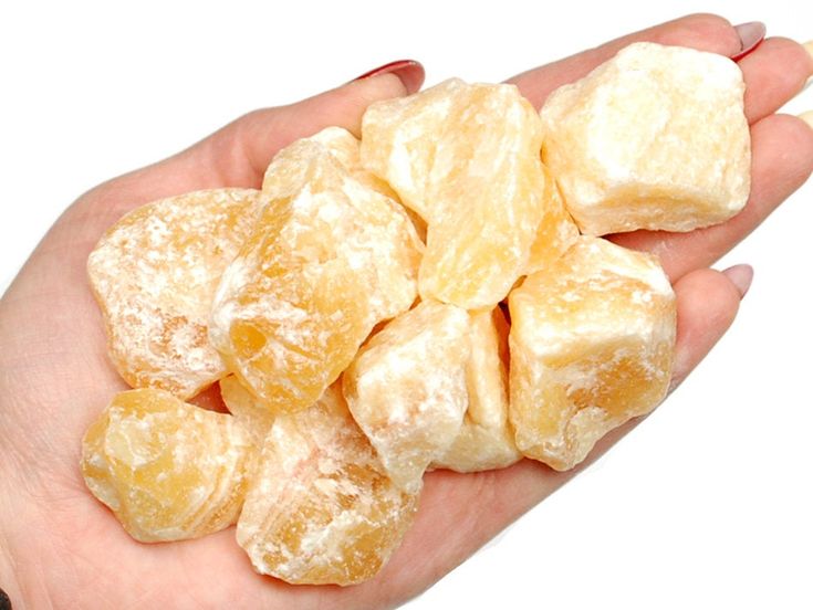 a person's hand holding small pieces of sugared doughnuts on white background