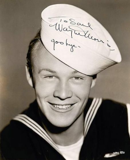 a black and white photo of a man wearing a sailor's hat with writing on it