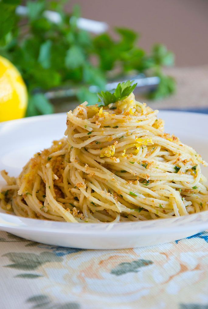 a white plate topped with spaghetti and garnished with parsley on the side