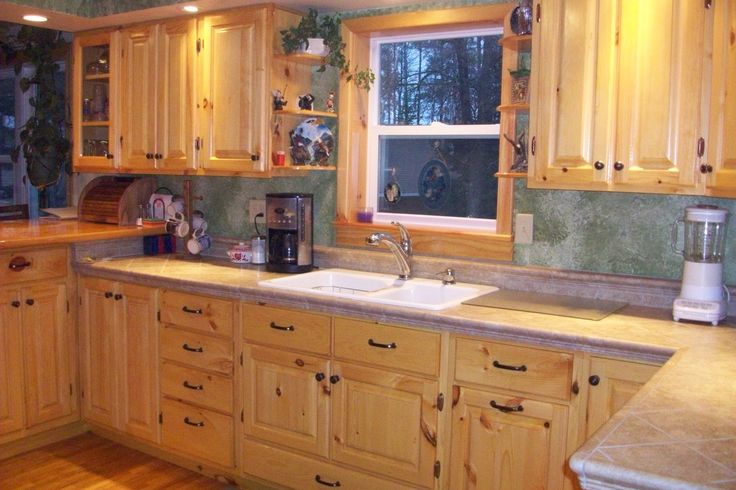 a kitchen filled with lots of wooden cabinets and counter top space next to a window