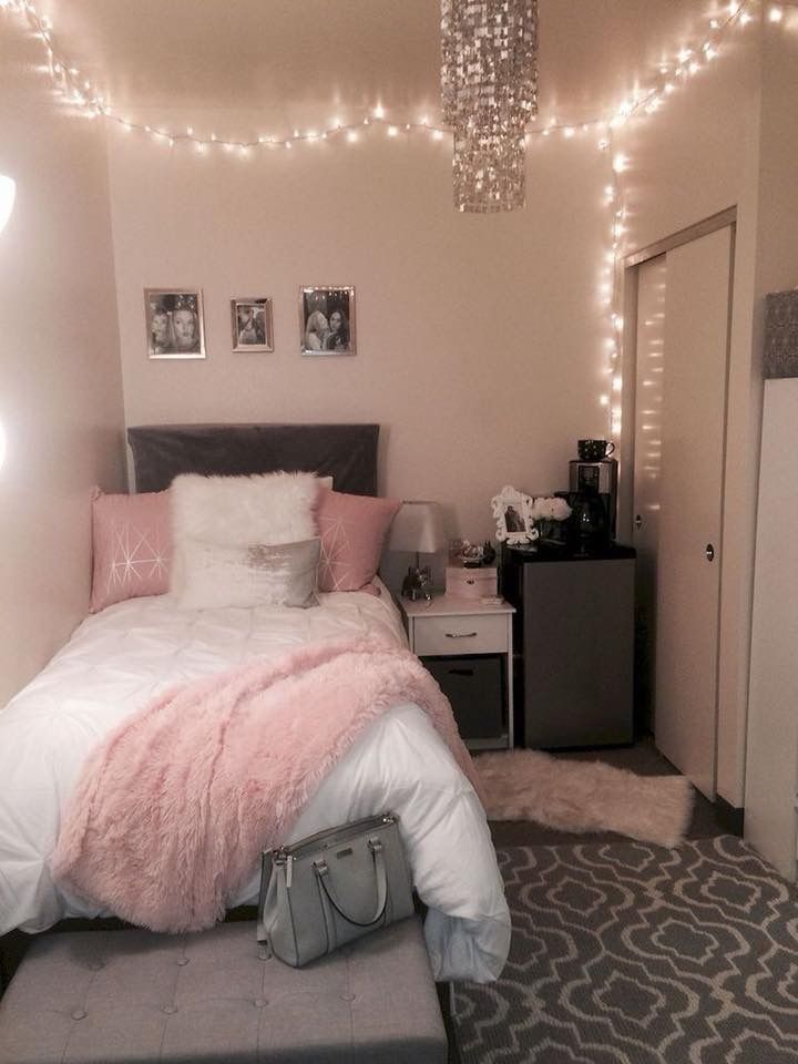 a bedroom decorated in pink and white with lights strung above the bed, luggage on the floor