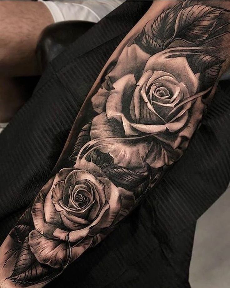 a black and white rose tattoo on the right arm, with three roses in it