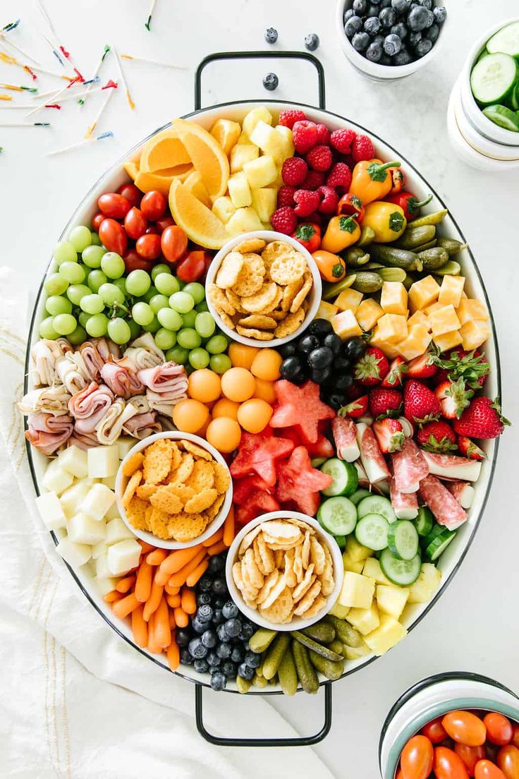 a platter filled with different types of fruits and veggies on top of a white table