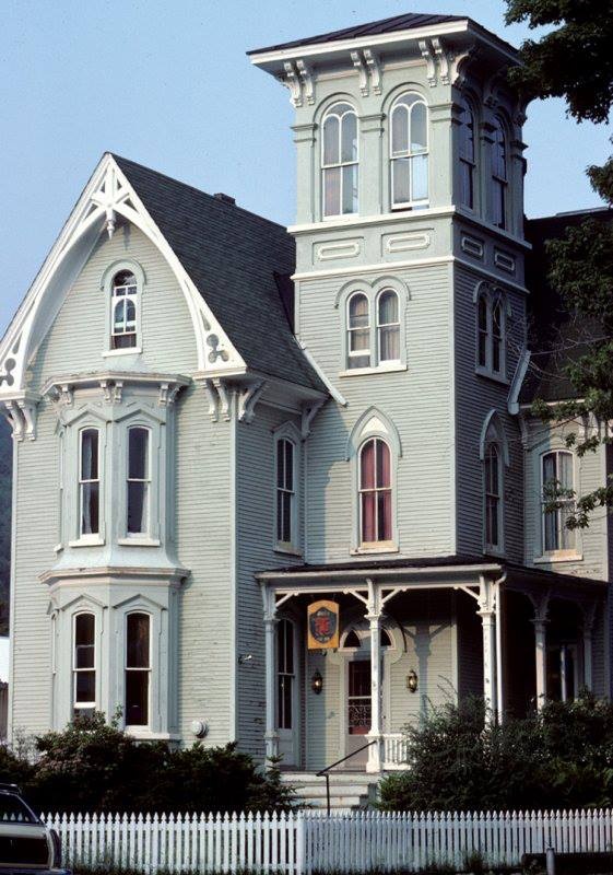 a large gray house with a white picket fence