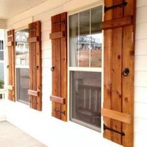 two windows with wooden shutters on the side of a house