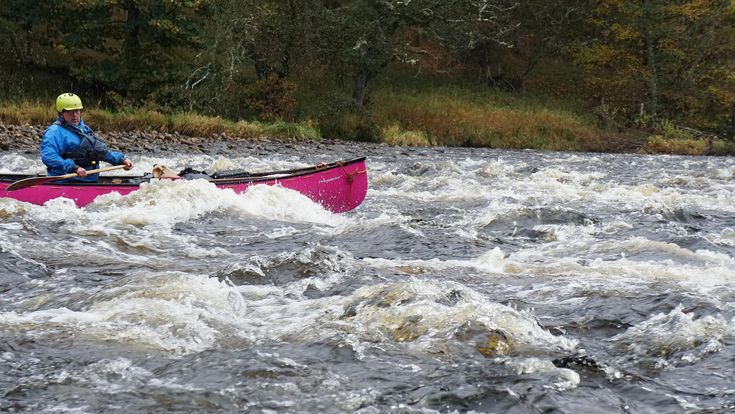 a man in a pink kayak paddling through rapids