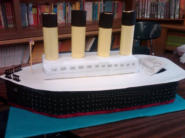 a cake made to look like a cruise ship with four candles on top and one candle in the middle