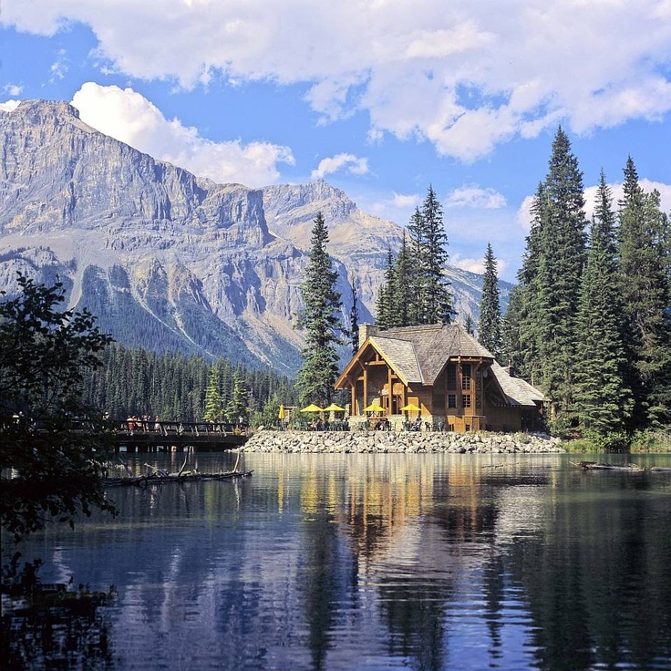 a lake surrounded by trees and mountains under a blue sky