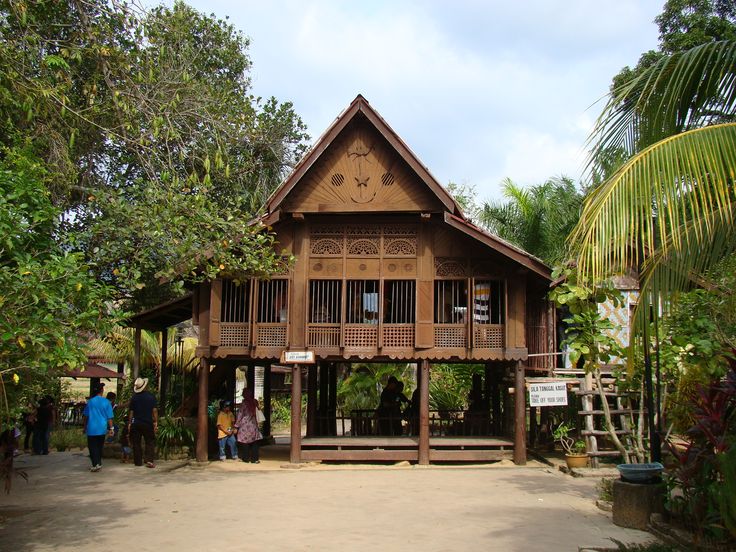 an old wooden house surrounded by trees and people