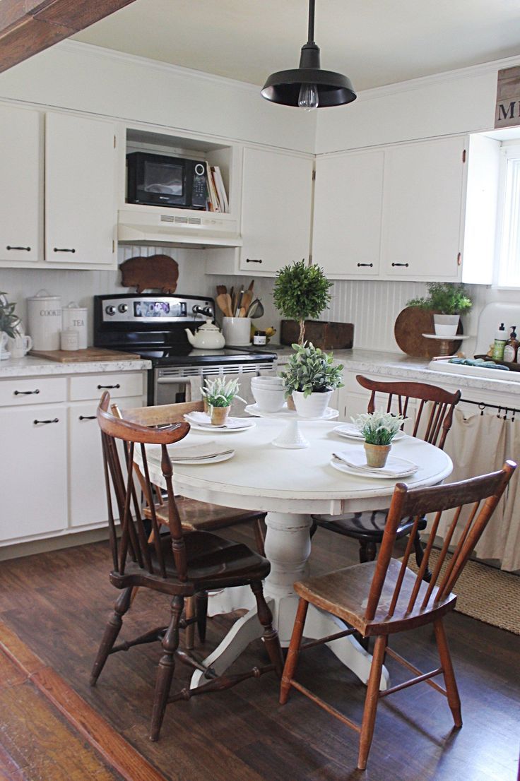 a kitchen table with four chairs around it in front of an oven and microwave on the wall