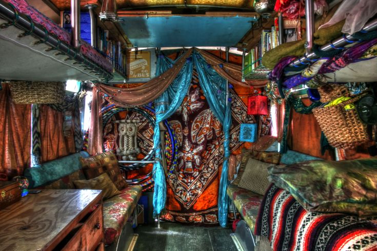 the inside of a bus with colorful curtains and bedspreads on the floor