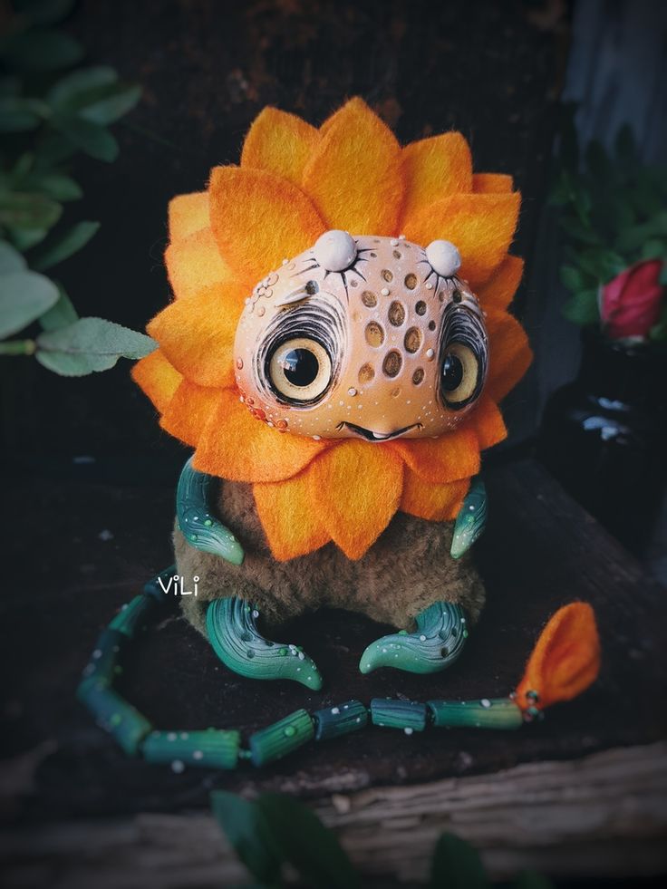 a stuffed animal sitting on top of a wooden table next to flowers and plants in the background