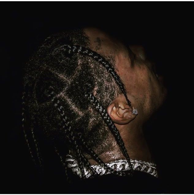 a man with dreadlocks on his head looking down at something in the dark