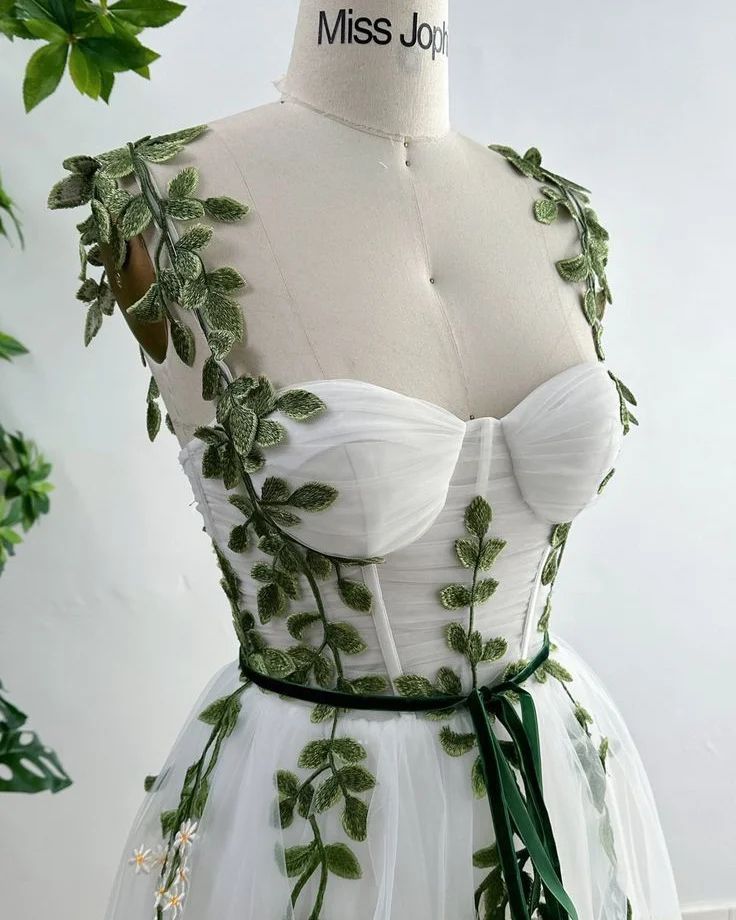 a white dress with green leaves on it