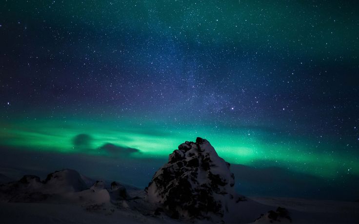 the sky is filled with green and blue lights as it shines above snow covered mountains