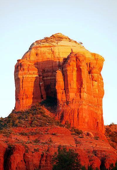 an orange rock formation with trees in the foreground