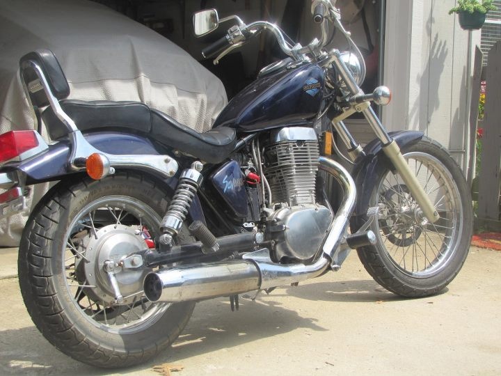 a blue motorcycle parked in front of a garage