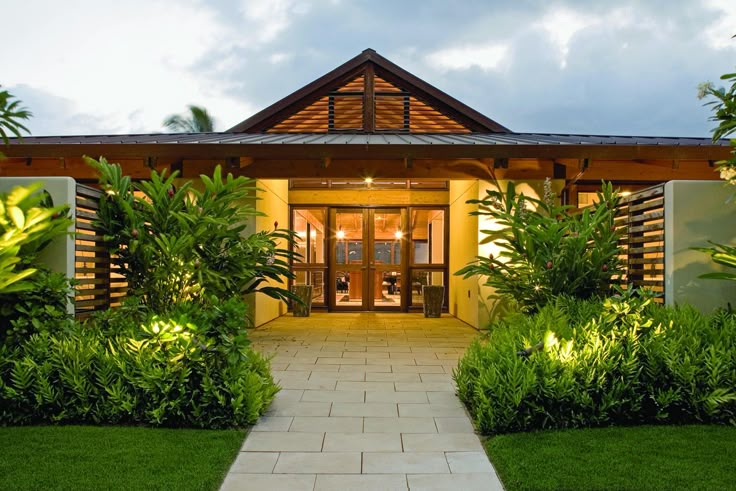 the entrance to a tropical home lit up with lights and greenery on either side