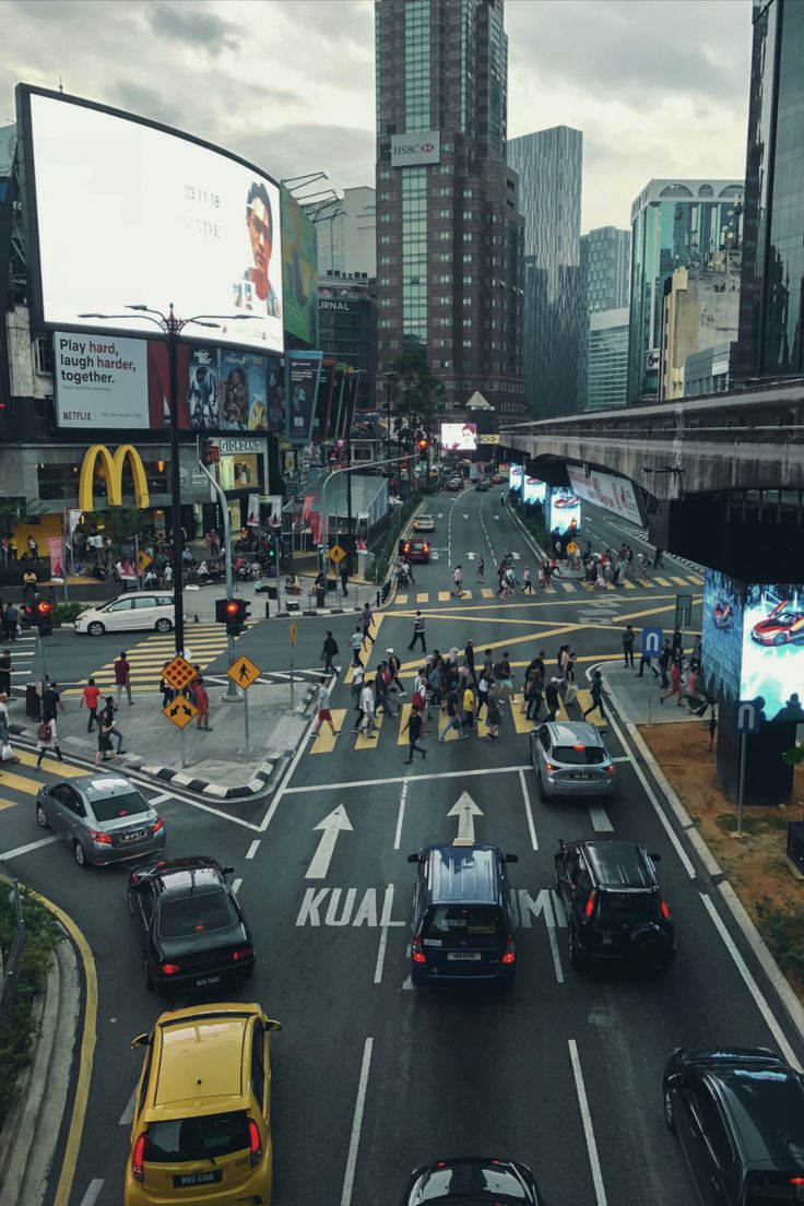 a busy city street filled with lots of traffic next to tall buildings and tall skyscrapers